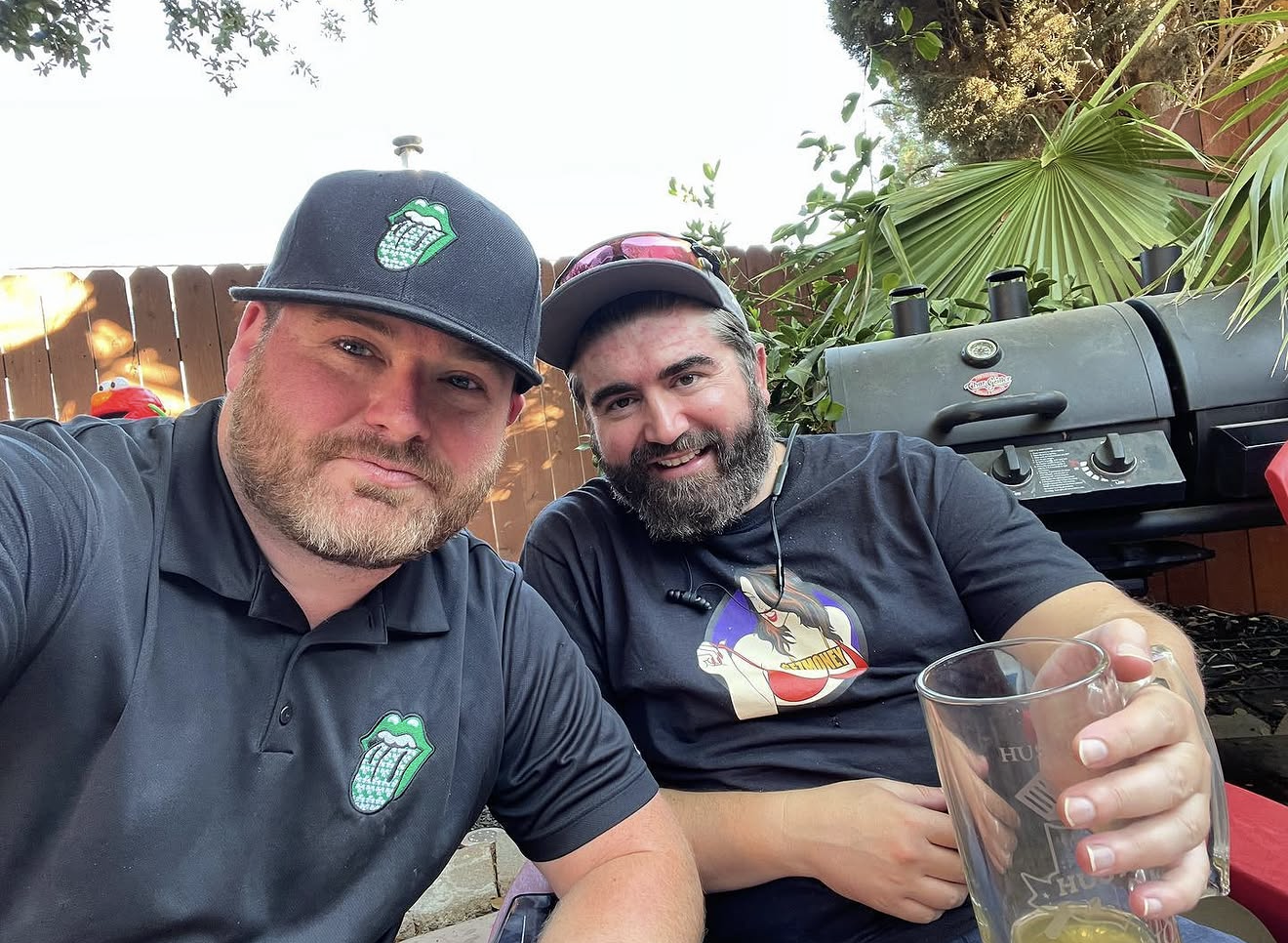 Two Sunday Hu$tle owners hanging by the grill with Hu$tle pint glasses