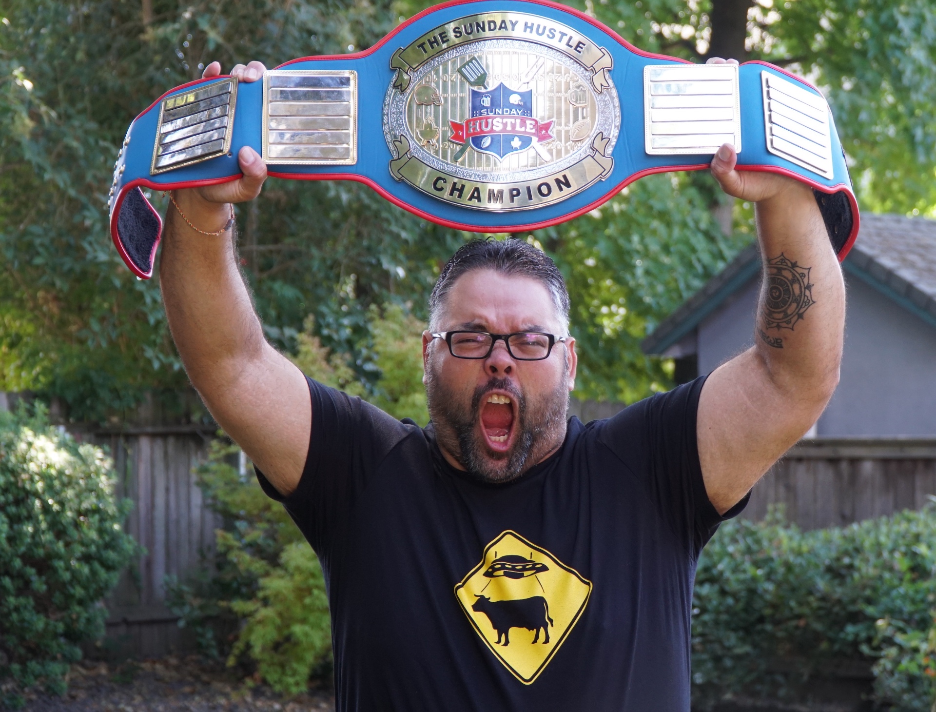 Sunday Hu$tle owner raising the championship belt overhead and yelling